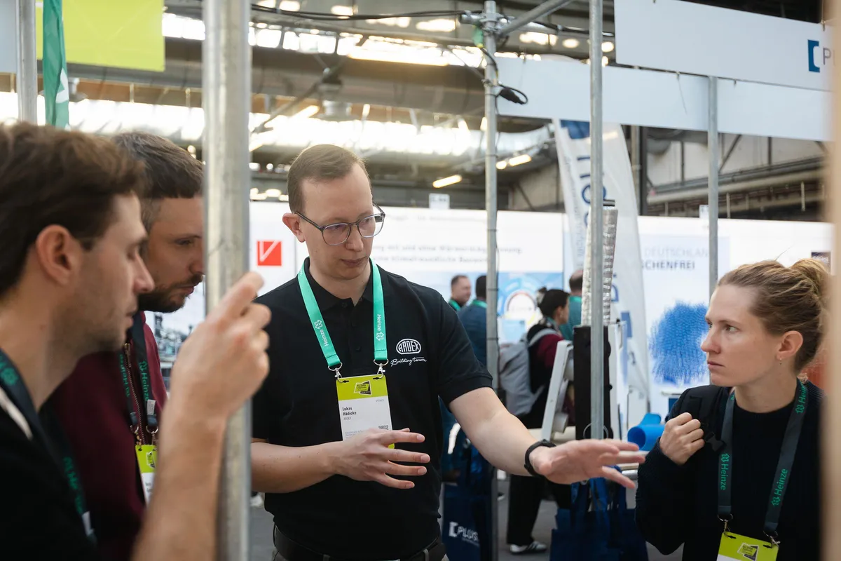 Lukas Hädicke von Ardex erklärt Besucher:innen am Messestand auf dem Heinze Klimafestival 2025 das Standkonzept