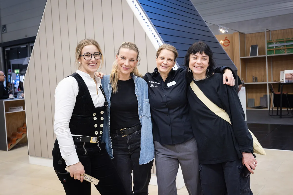 Sina Klein und drei Frauen stehen Arm in Arm am Messestand von Cedral und Eternit