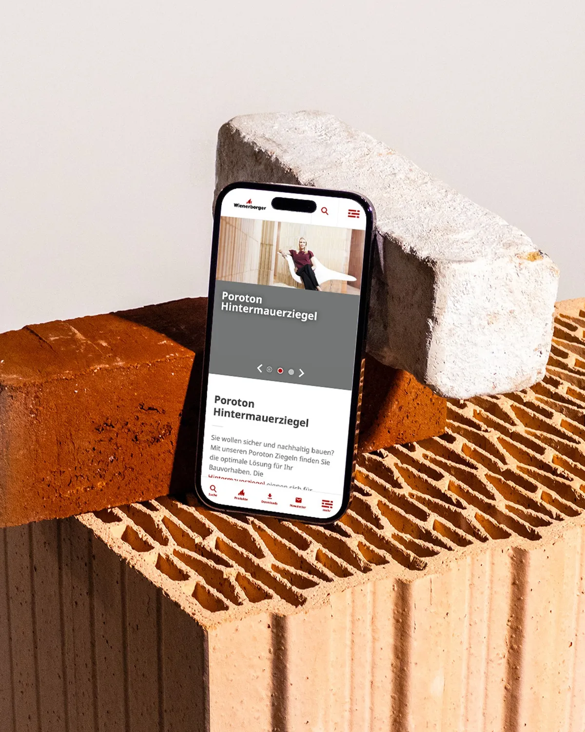 Smartphone mit der mobilen wienerberger-Website zu Poroton Hintermauerziegeln, angelehnt an verschiedene Ziegel