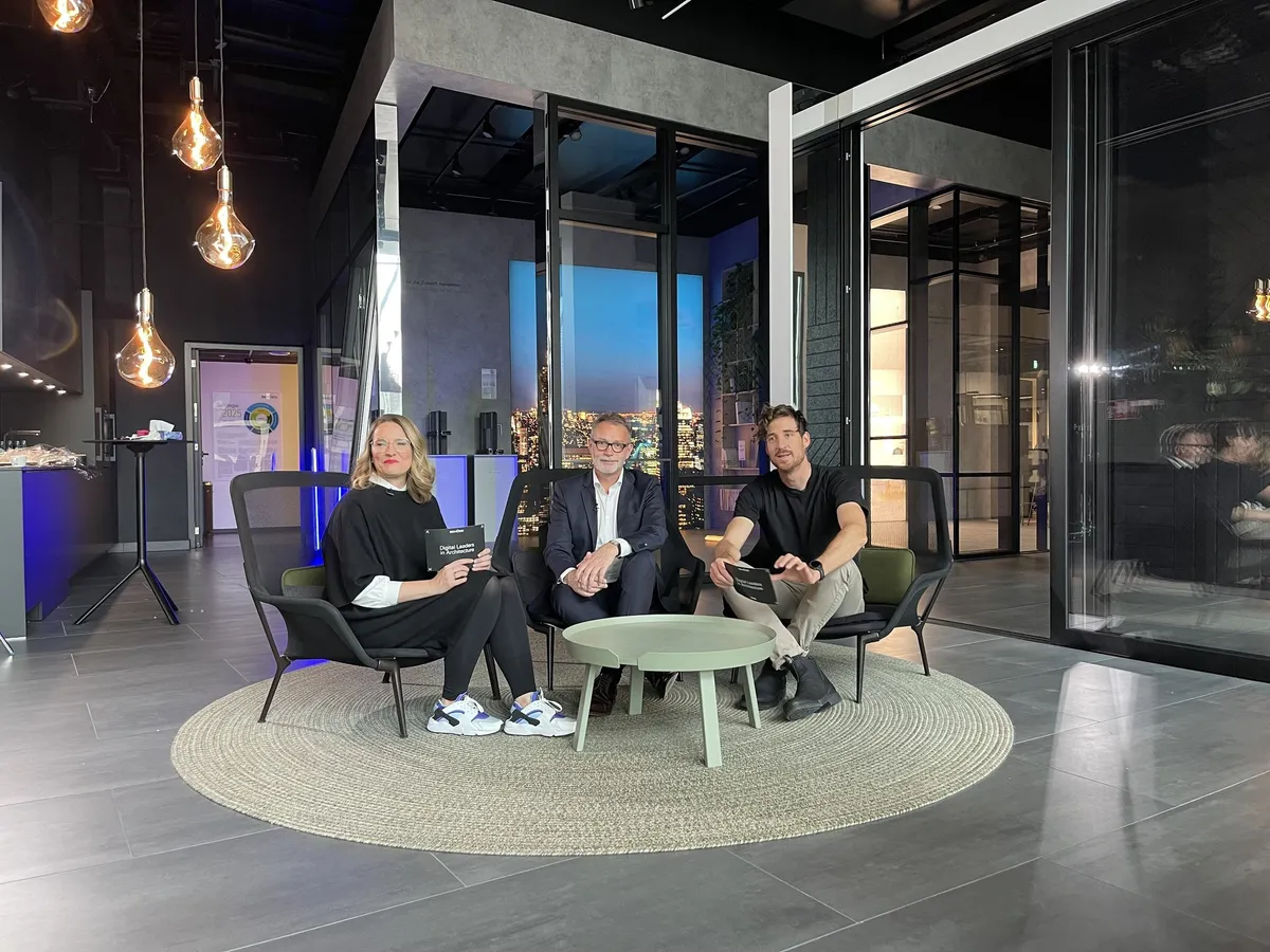 Abendlicher Dreh im Schüco Showroom Frankfurt: Gesprächsrunde zu dritt in Sesseln auf einem runden Teppich unter Glühbirnenleuchten