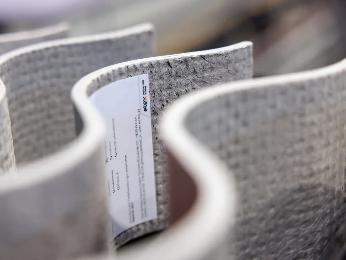 Nahaufnahme gewellter grauer Faserzementplatten mit Etex-Musteretikett