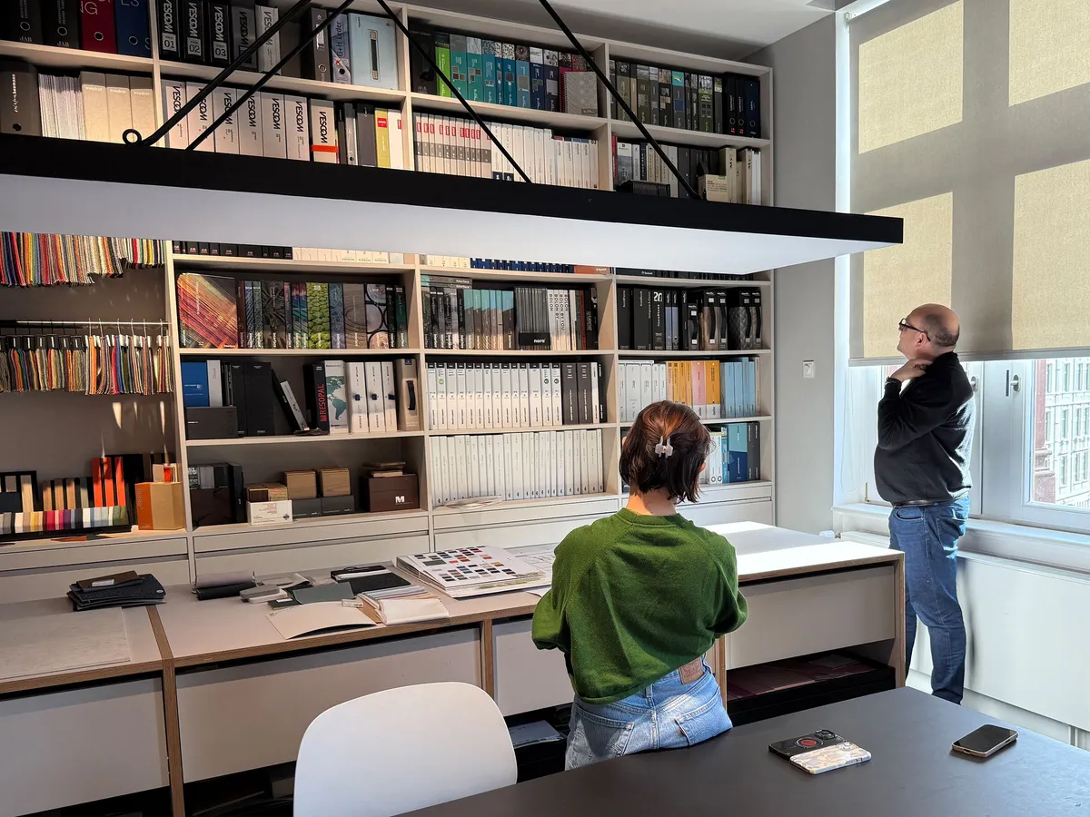 Materialbibliothek von Just Architekten mit Regalen voller Musterordner und Materialproben, zwei Personen bei der Arbeit