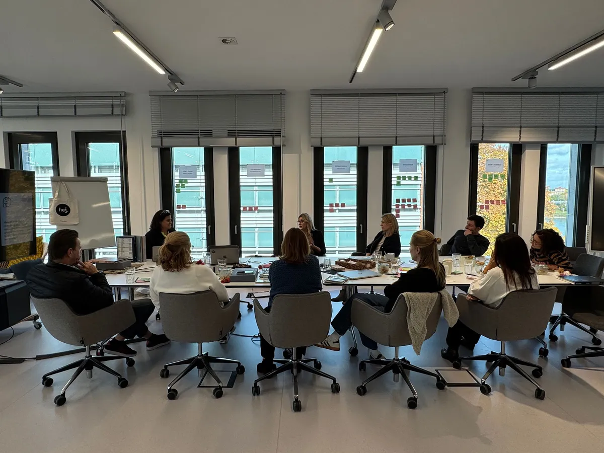 Workshop mit dem Tarkett-Team an einem großen Konferenztisch in einem hellen Besprechungsraum mit hohen Fenstern