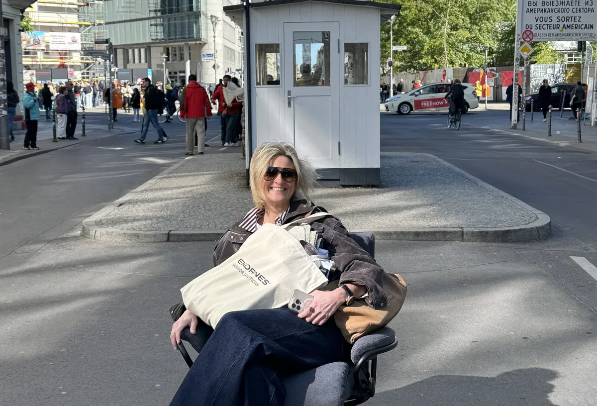 Eine Frau sitzt in einem Stressless-Sessel mitten auf der Straße am Checkpoint Charlie in Berlin