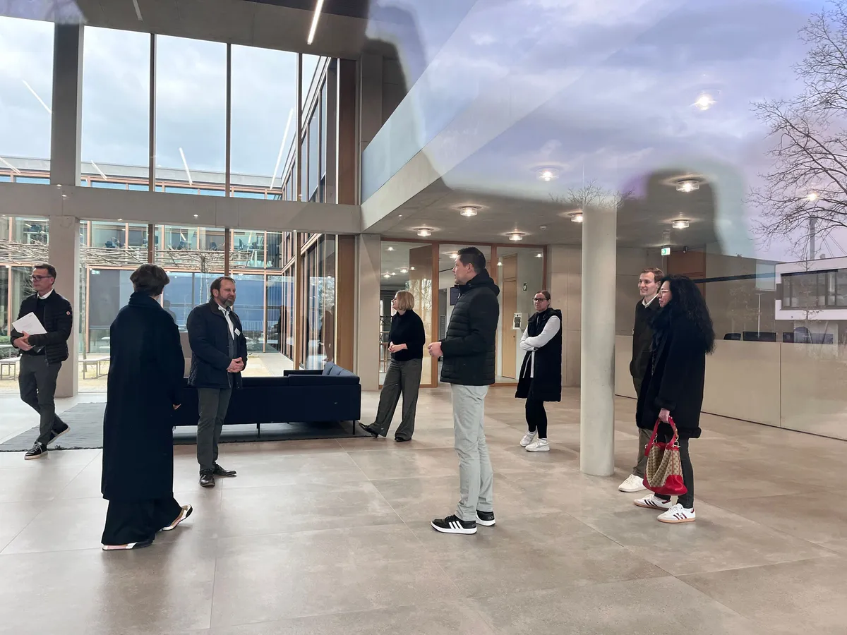 Teilnehmende des TECE Strategieworkshops im Gespräch in einem hohen, verglasten Foyer