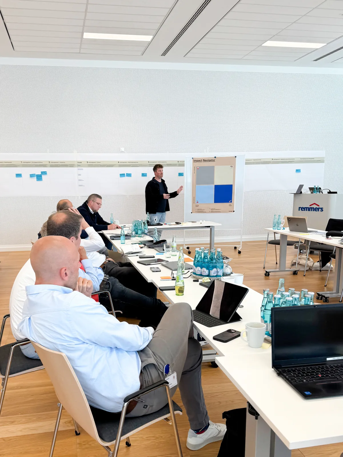 Vortrag vor dem Remmers-Team, das an langen Tischen in einem hellen Seminarraum sitzt
