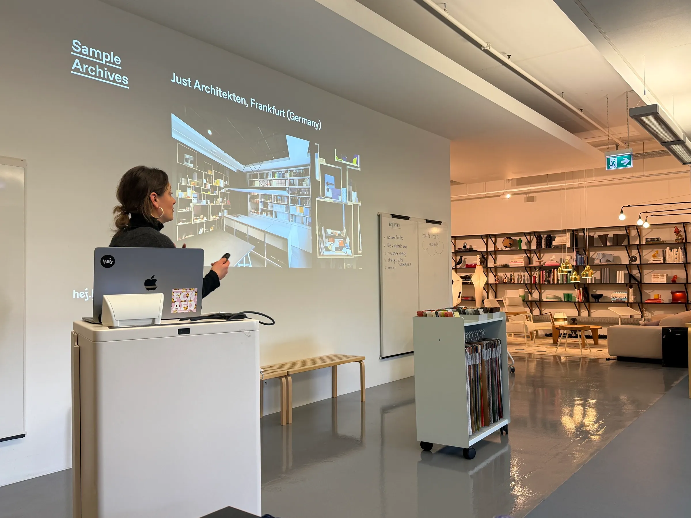 Referentin vor einer Projektion zum Thema »Sample Archives« in einem Showroom mit Materialregalen