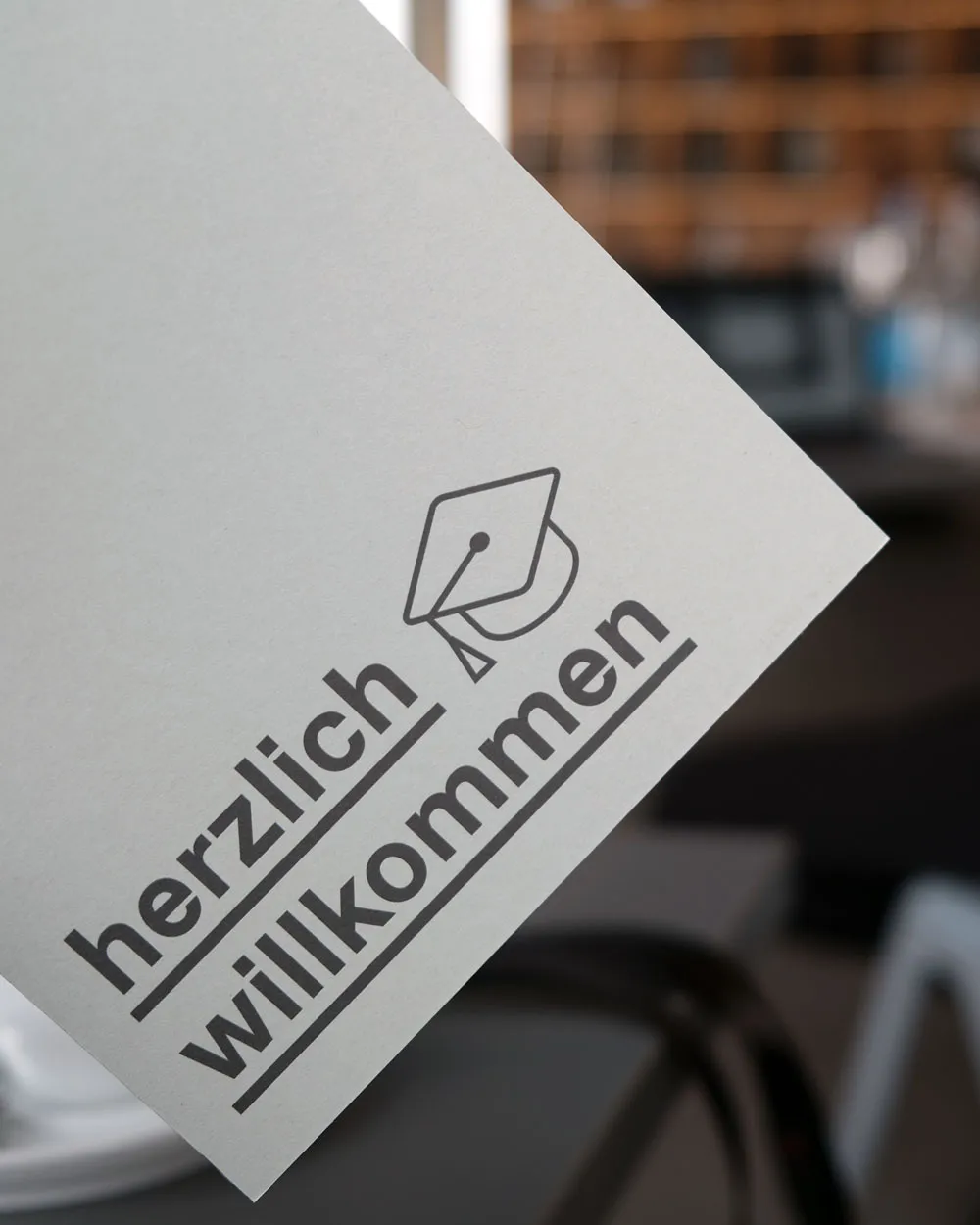 Karte mit der Aufschrift »herzlich willkommen« vor einem Schreibtisch