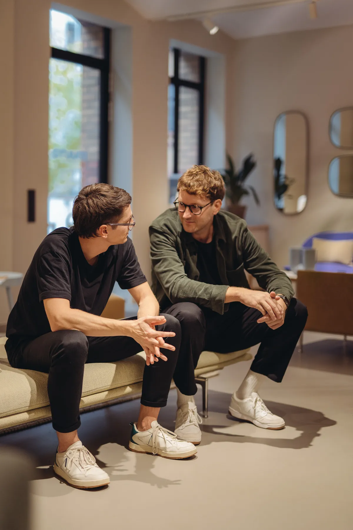 Zwei Teilnehmende im Gespräch auf einem Sofa in einem hellen Showroom