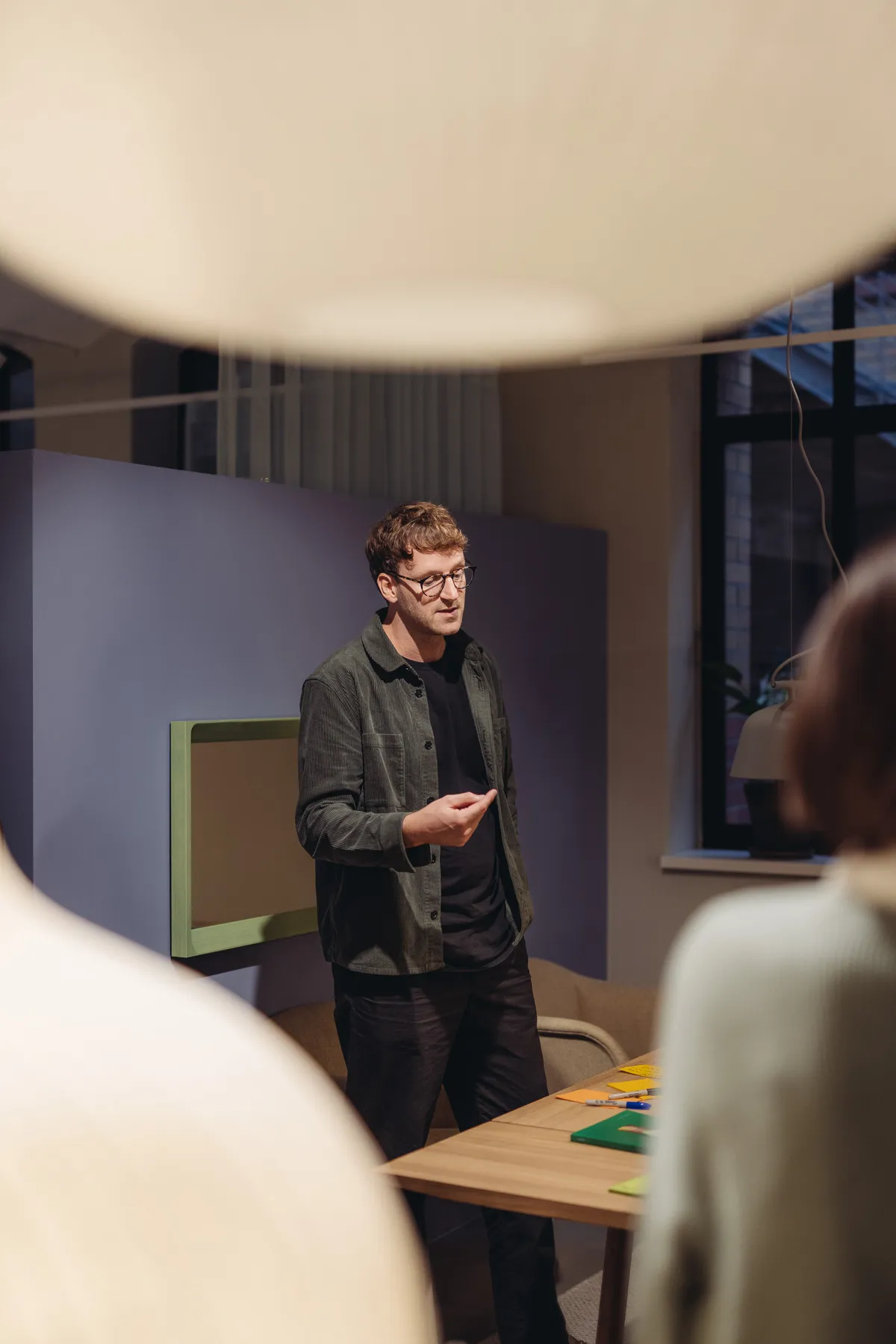 Person mit Brille spricht in einem Workshopraum zur Gruppe