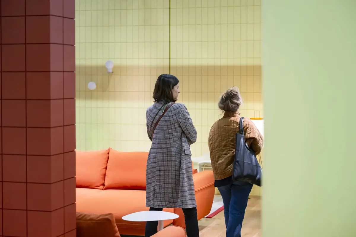 Stand von mdd in Halle 4 auf der Orgatec, zwei Besucher:innen betrachten eine Ausstellungsfläche mit modernen Möbeln.