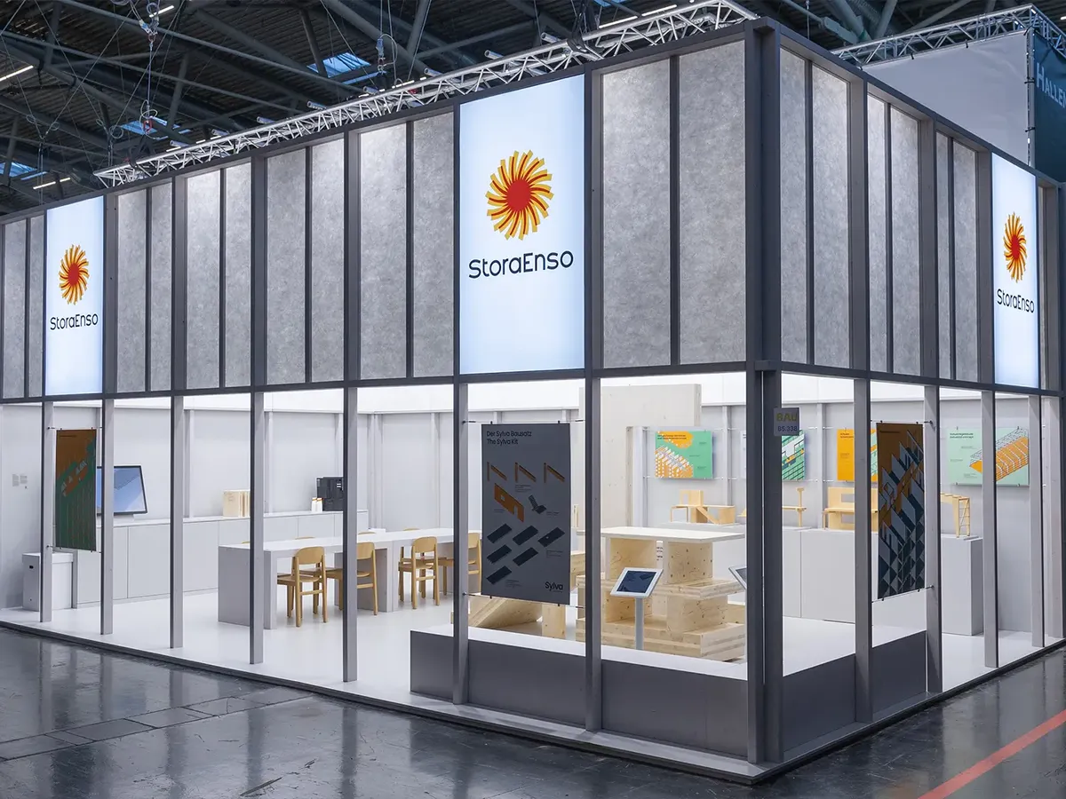 Minimalistischer Stora Enso Messestand auf der BAU 2025 mit klarer Raumaufteilung, technischen Produktvisualisierungen und Beratungszonen in Holz und Weiß