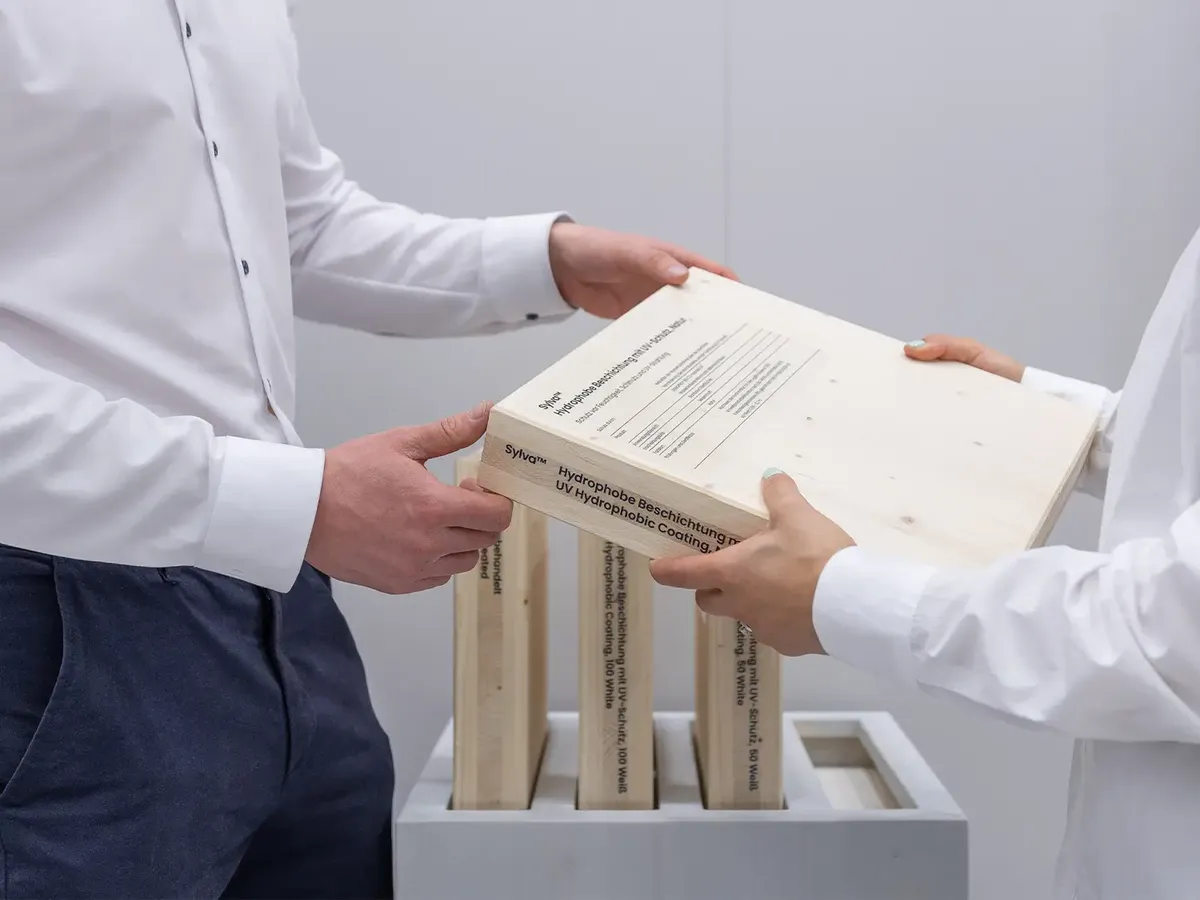 Detailaufnahme einer Produktübergabe am Stora Enso Stand: technische Dokumentation zur hydrophoben Beschichtung Sylva
