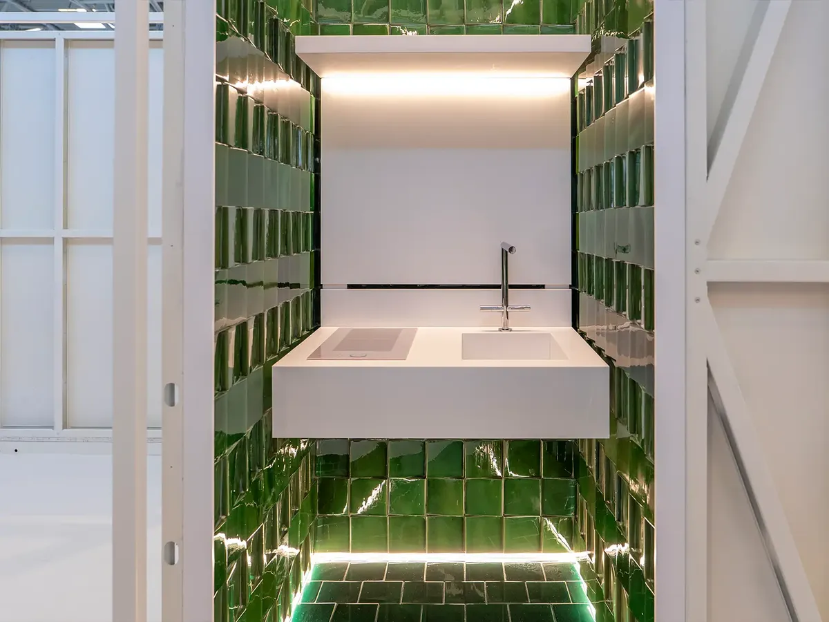 MODS Sanitärbox: minimalistisches Waschbecken umgeben von grün glasierten Wandfliesen mit stimmungsvoller LED-Beleuchtung
