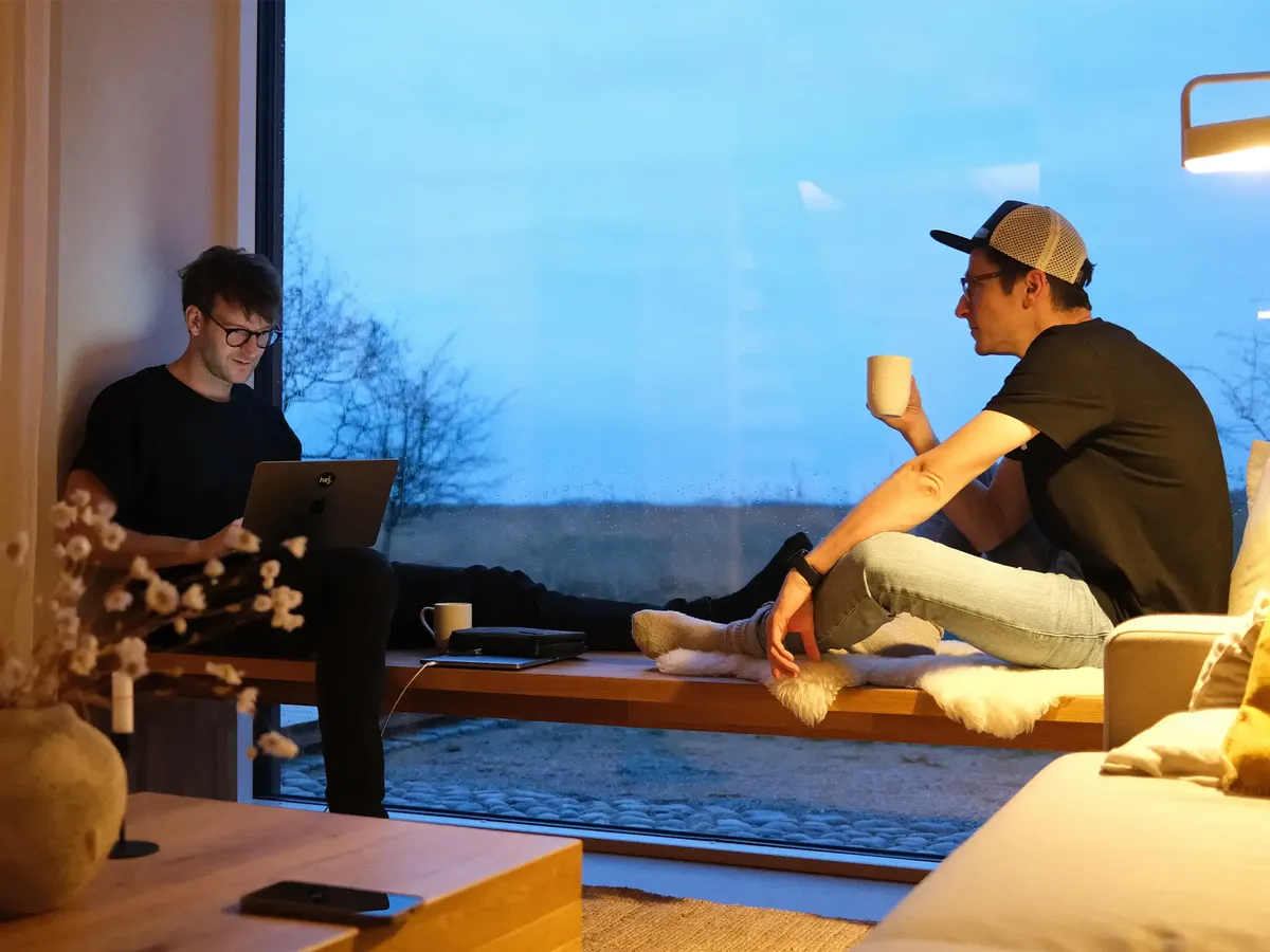 hej.build Gründer Hannes Eberlein und Michael Rahmfeld bei einer strategischen Besprechung am Fenster, Symbol für die flexible und fokussierte Arbeitsweise der Remote-Strategieberatung.