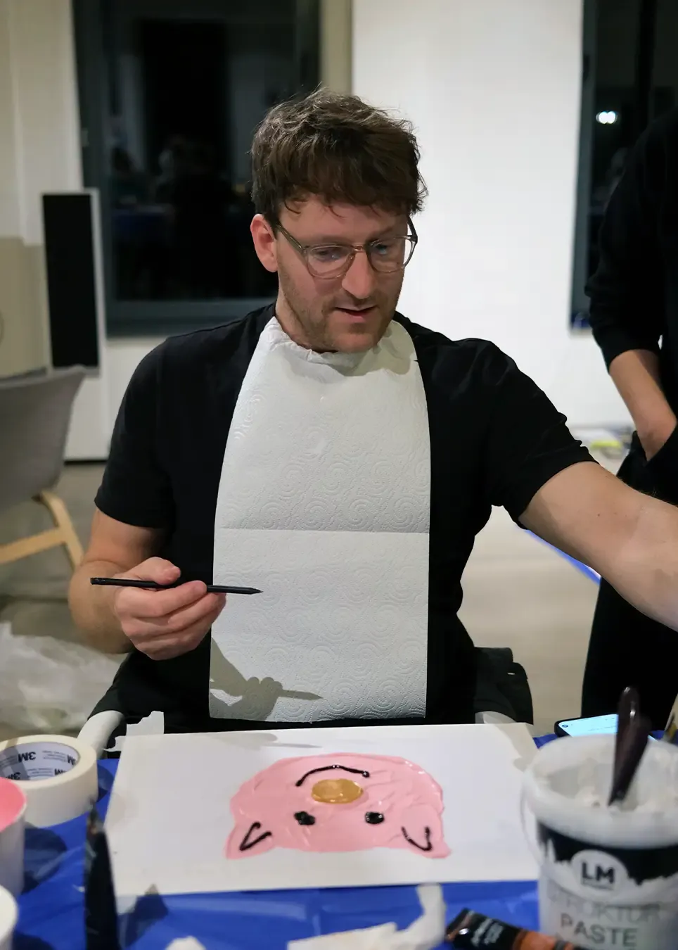 hej.build Co-Gründer konzentriert beim Bemalen einer Sparschwein-Figur während eines kreativen Team-Events, Ausdruck der vielseitigen und humorvollen Unternehmenskultur der Strategieberatung.