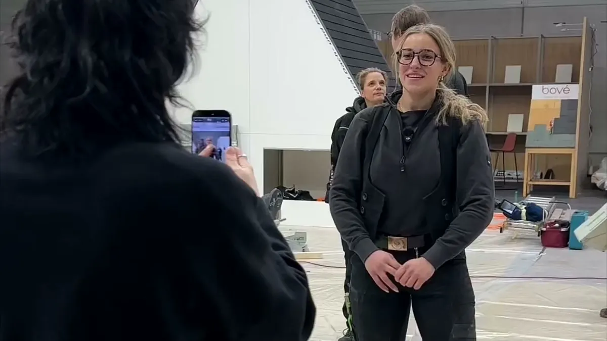 Master roofer Sina Klein at the Cedral and Eternit stand, a woman in the foreground filming her on a smartphone