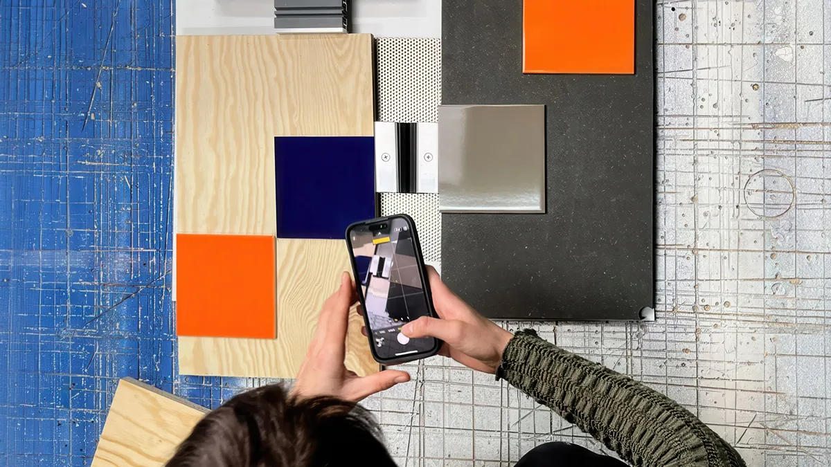 A person photographing a collage of material and colour samples with a smartphone