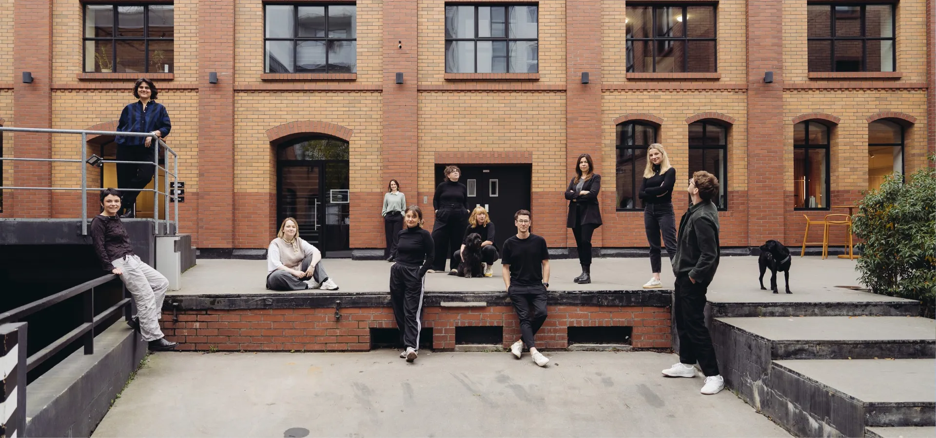 The hej.build team spread across the courtyard of a brick building, with a dog