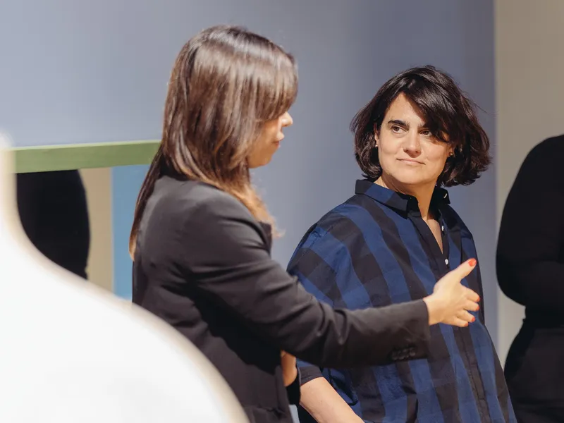 Two women talking in a showroom, one explaining something with an open hand