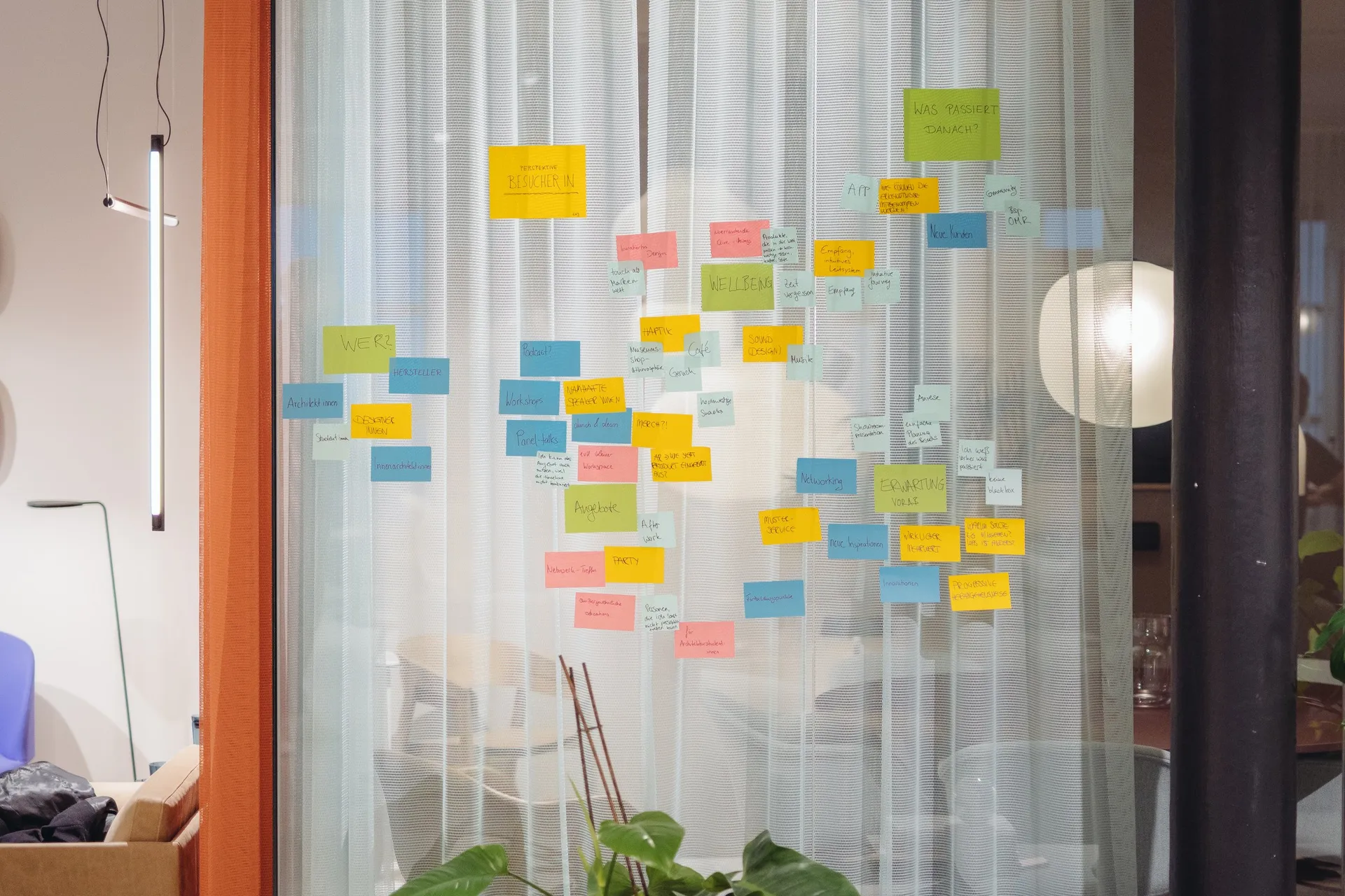 Glaswand voller bunter Haftnotizen in einem Showroom