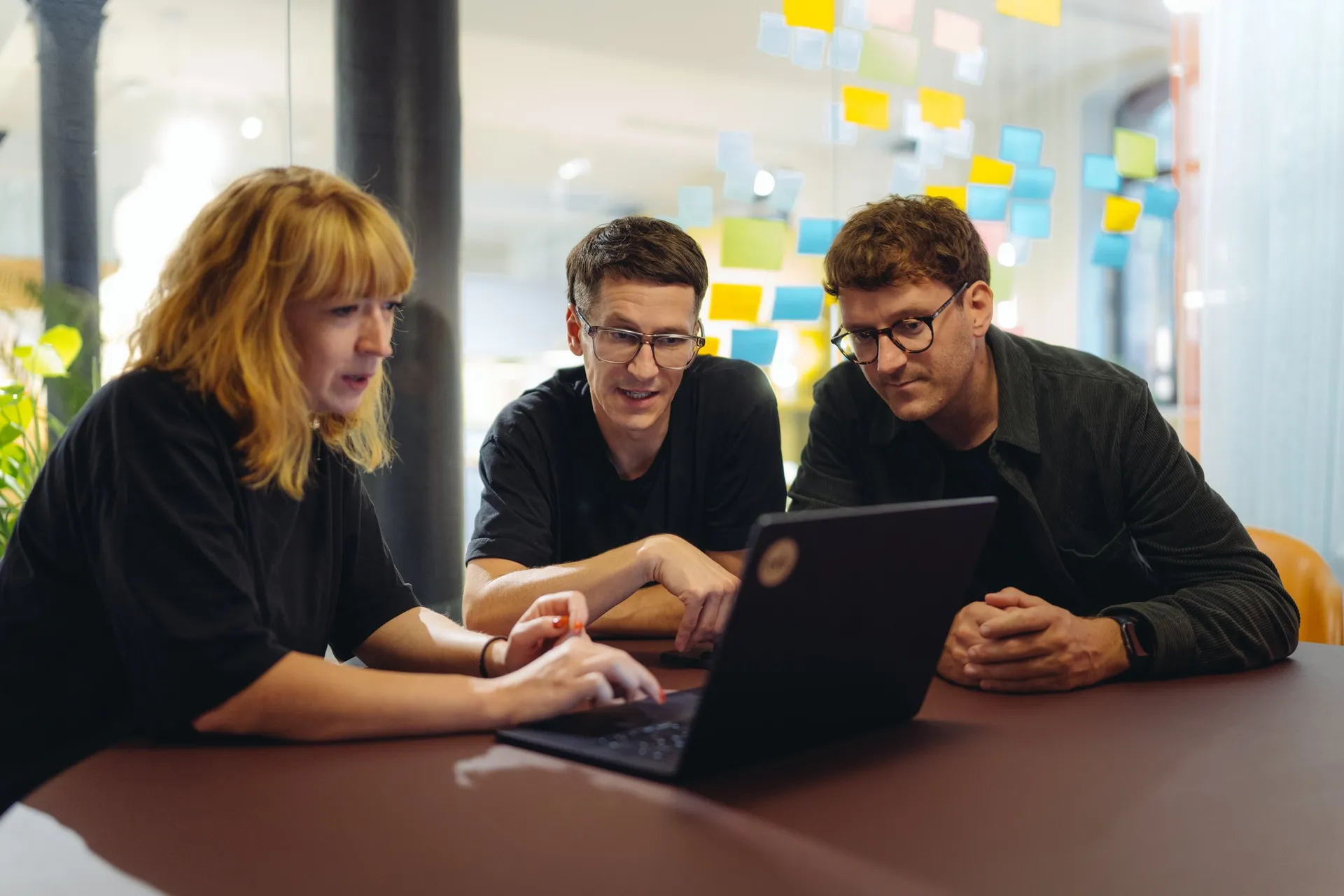 Drei aus dem Team schauen gemeinsam auf einen Laptop