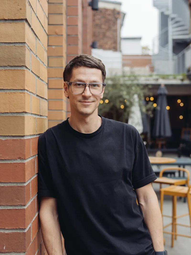 Michael Rahmfeld lehnt an einer Backsteinwand, im Hintergrund ein Innenhof mit Lichterketten
